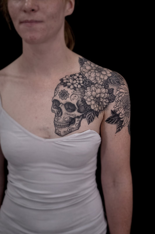 Woman with a chest tattoo of flowers and a skull