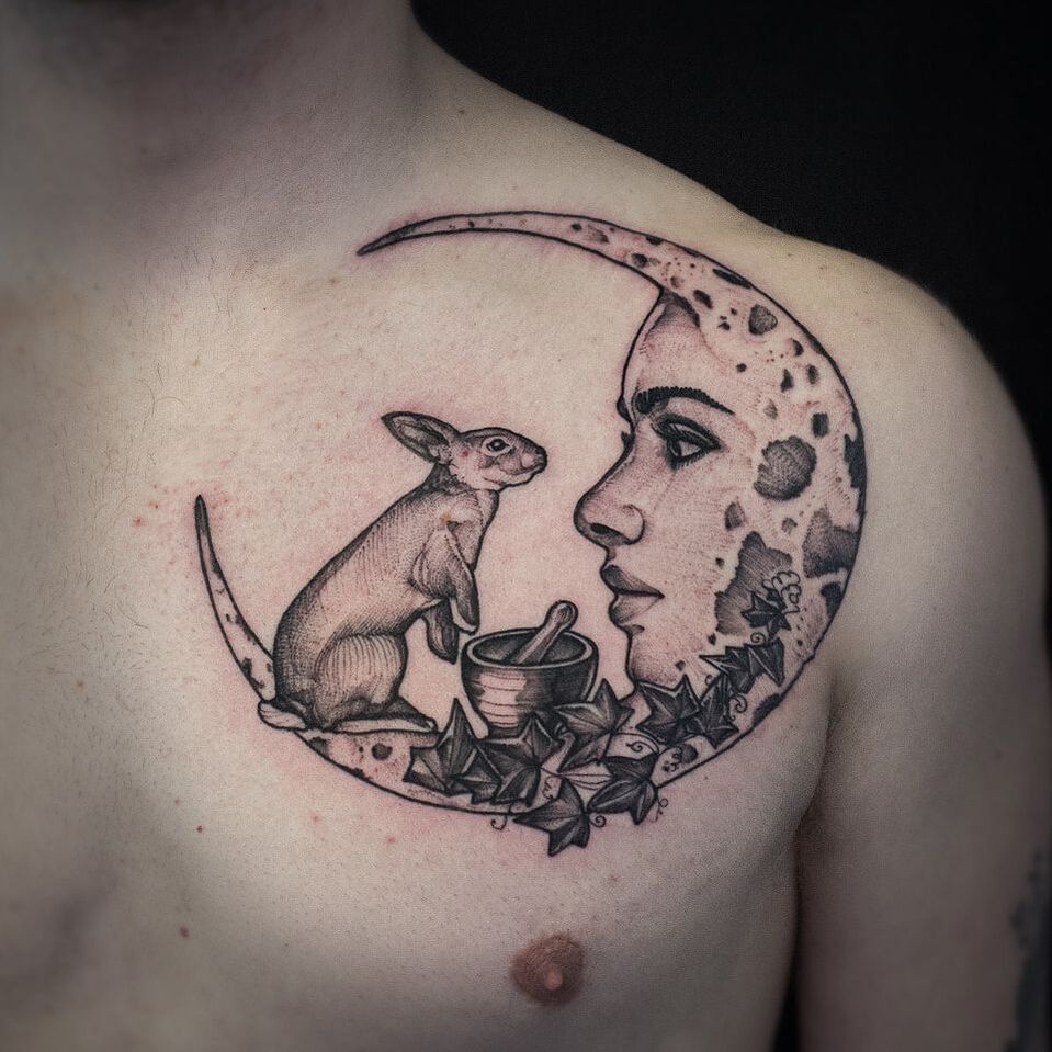Moon with face and a rabbit mans chest tattoo
