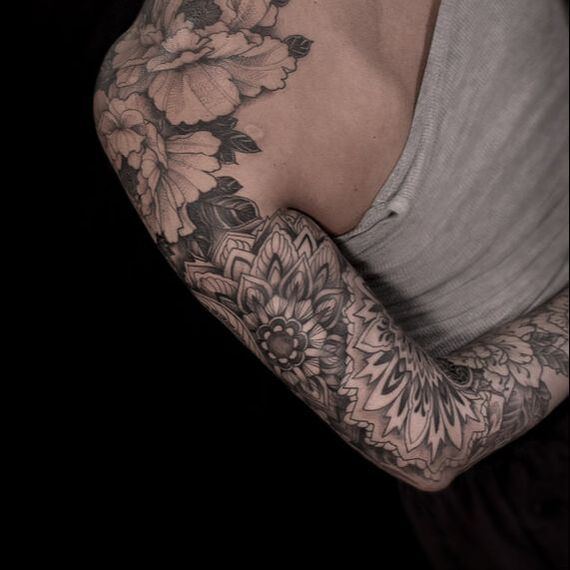 A geometric tattoo sleeve on a woman displayed in an artistic photo