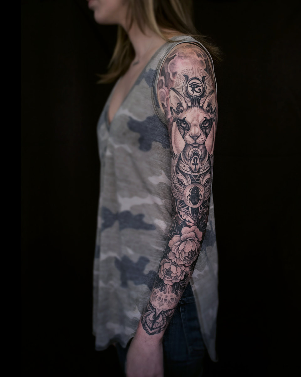 Woman with a full sleeve tattoo of an egyptian cat