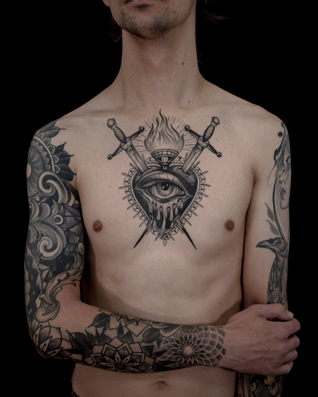 A heavily tattooed man with a sacred heart chest tattoo by artist Adam LoRusso