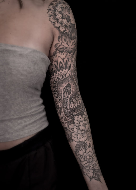 Woman with a tattoo sleeve of a geometric snake and mandala